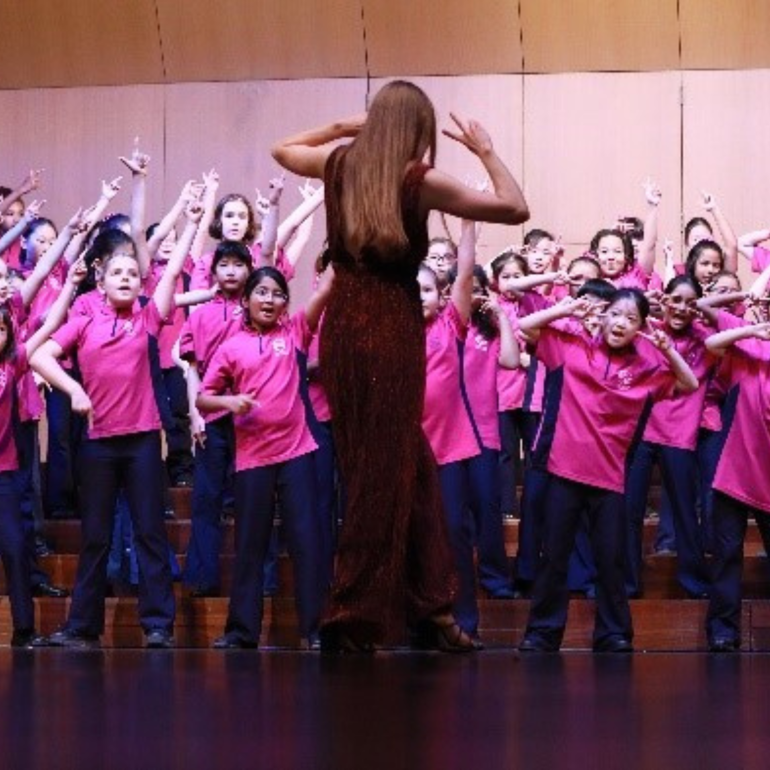 Alice strikes a pose as she conducts a group of AGC choristers on stage