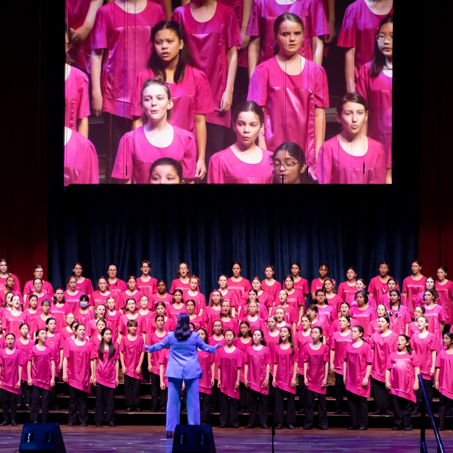 Grace faces away from the camera as she conducts a large group of AGC choristers