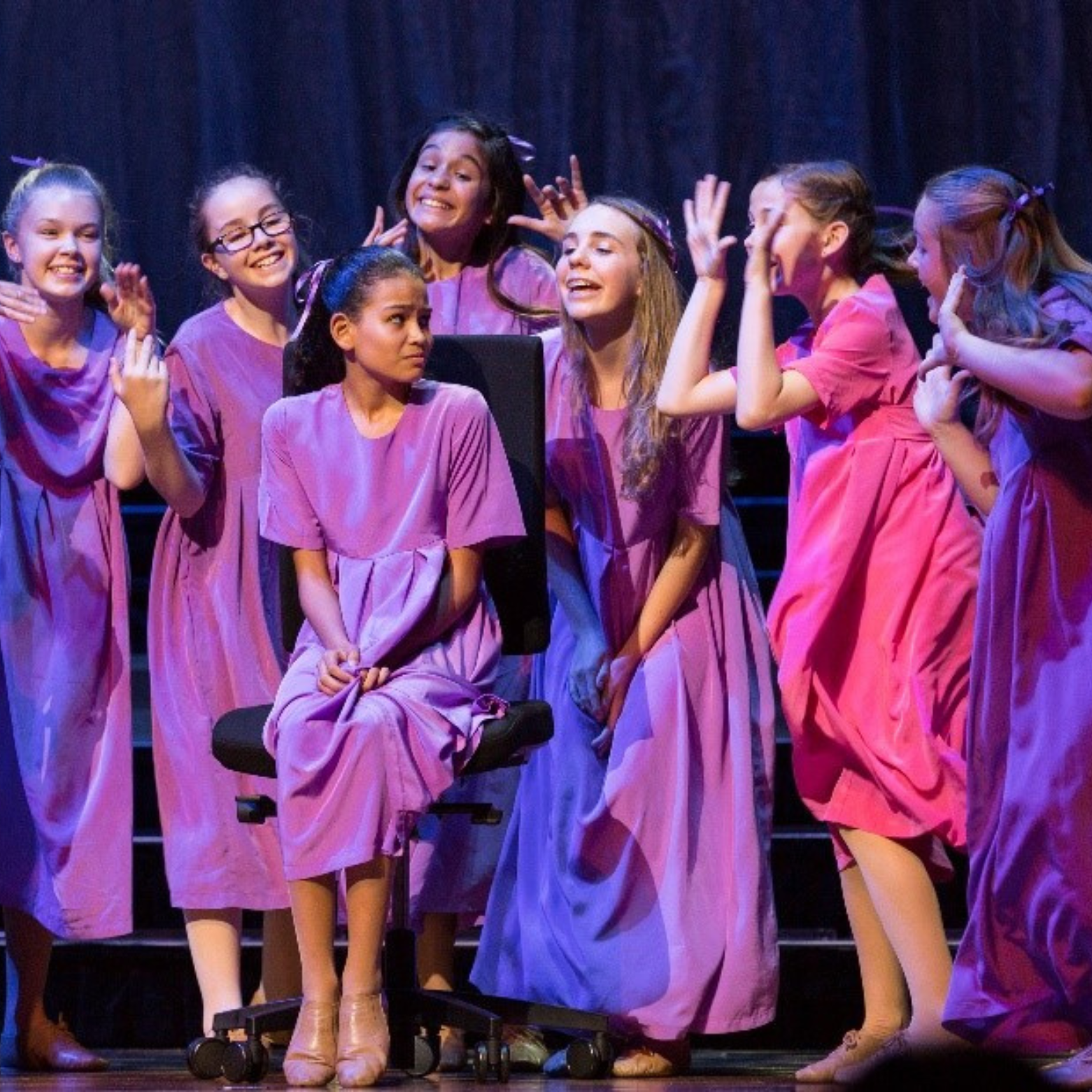 Alice performs as part of an ensemble. She pulls a funny face as she sings to the girl in front of her.