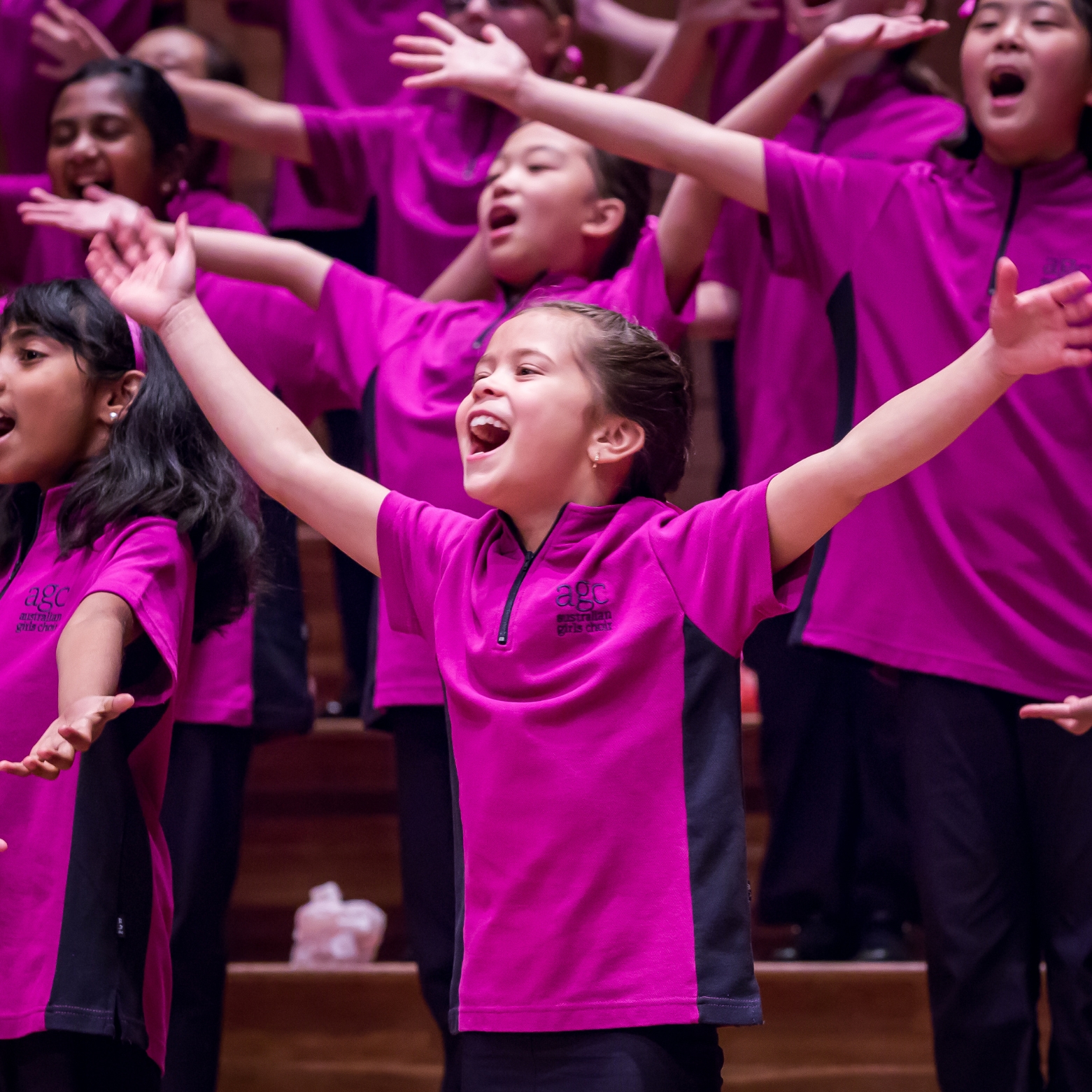 Girl sings proudly with her arms out on stage