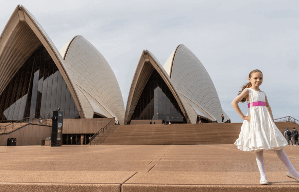 Young girl in white dress in front the Sydney Opera House